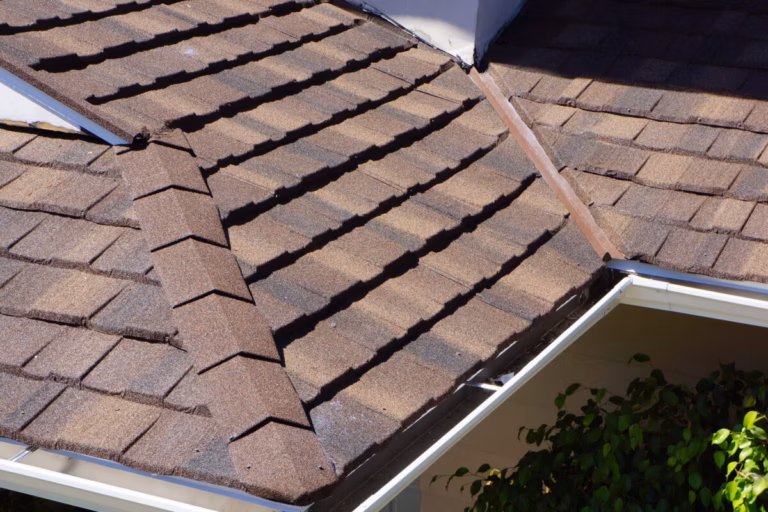 Close-up of color Barclay metal shingles installed on a residential roof, showing traditional shingle styling with overlapped rows and white guttering visible.