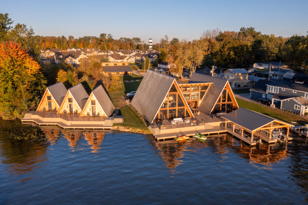 Aerial view of residential homes with peaked metal roofs and siding reflected in calm waterfront property