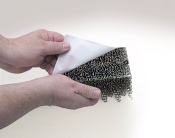 Two hands peeling a white fabric or paper backing layer away from a dark metal wire mesh ventilation closure strip against a plain light background.