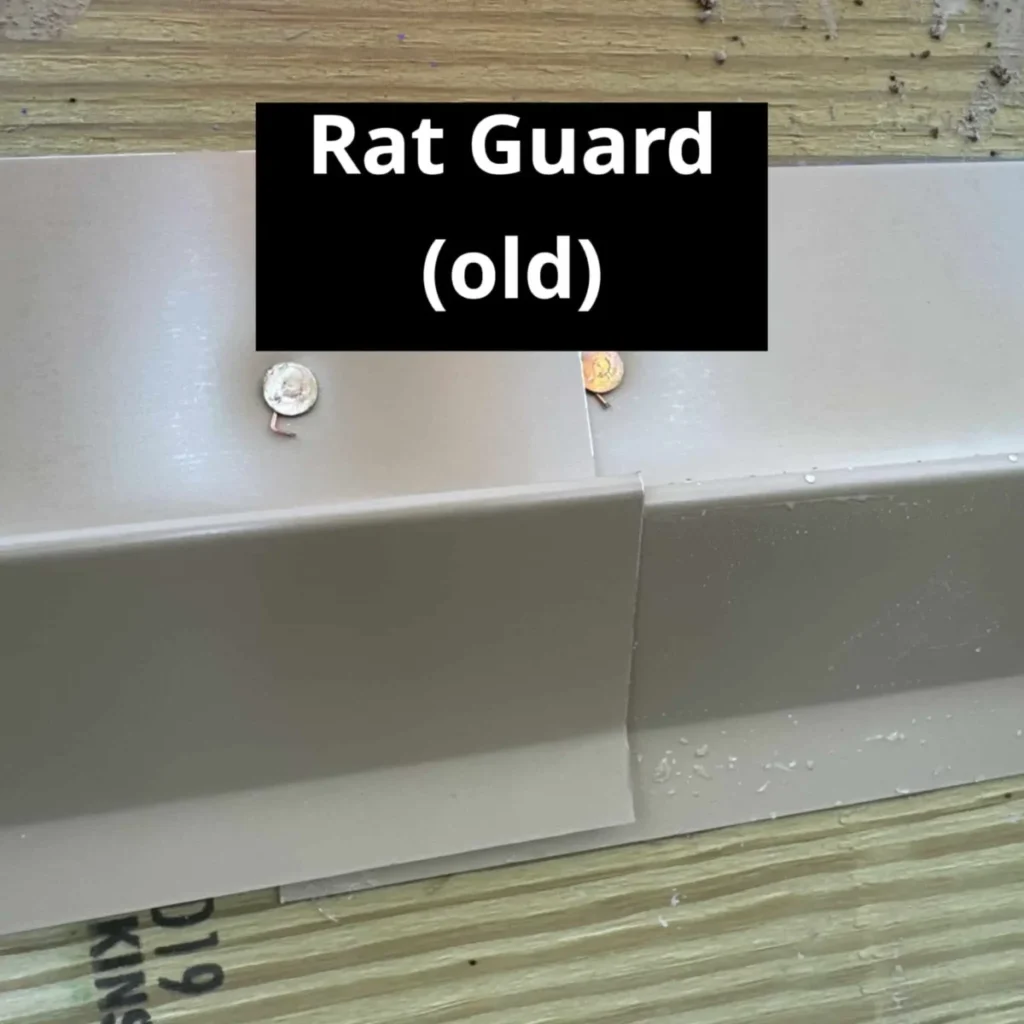 Two overlapping sections of an old gray metal rat guard fastened with small screws to stacked plywood sheets, showing the joint connection between panels.
