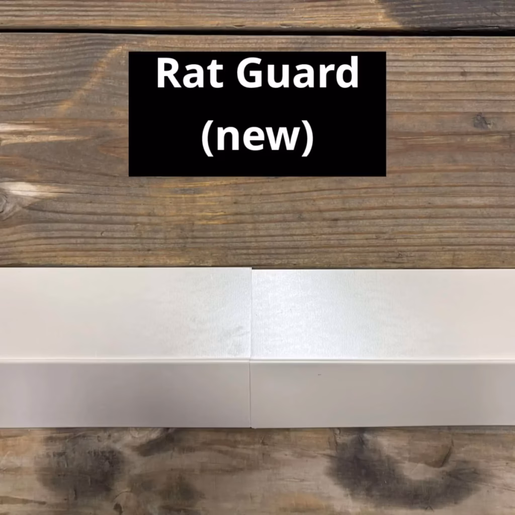 A new white metal rat guard panel displayed against a rustic wooden background, shown in two joined sections with a visible seam in the center.