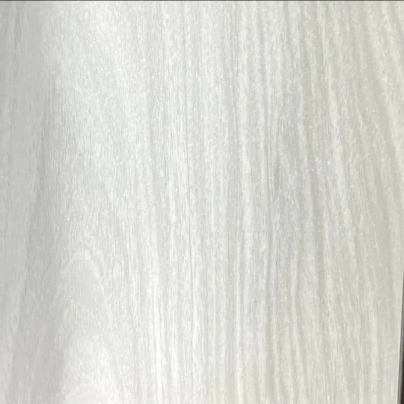 A close-up view of a white wood-grain decorative panel showing vertical grain patterns and subtle texture variations in pale gray and white tones.