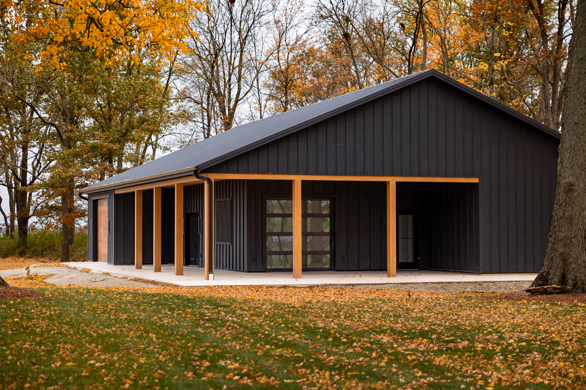 Single-story residential building with dark metal Buckeye wave siding and metal roof, featuring a covered porch with wooden support columns.