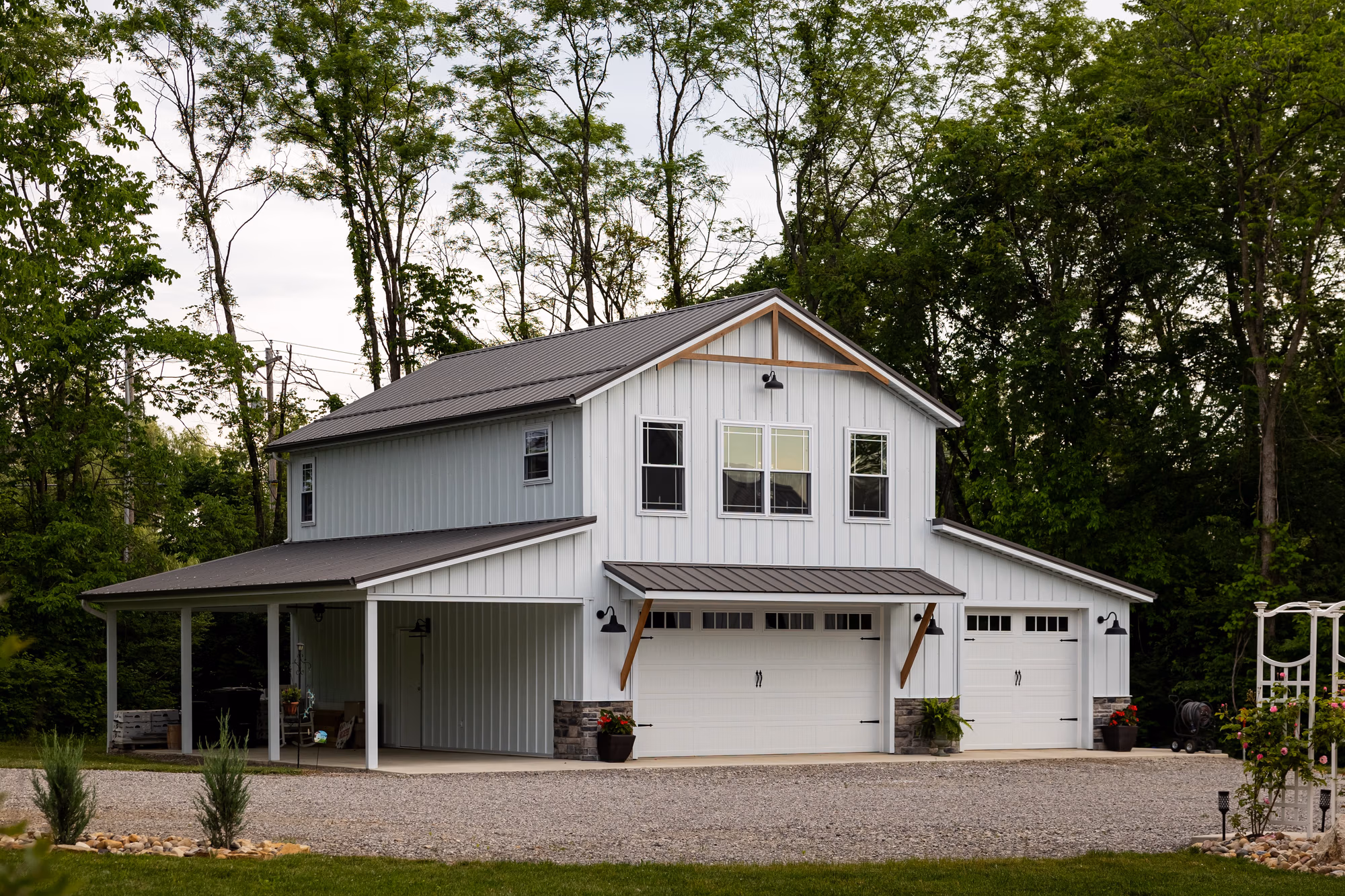 Two-story residential home with white Buckeye Wave metal siding panels and matching metal roof, covered front porch, and attached garage.