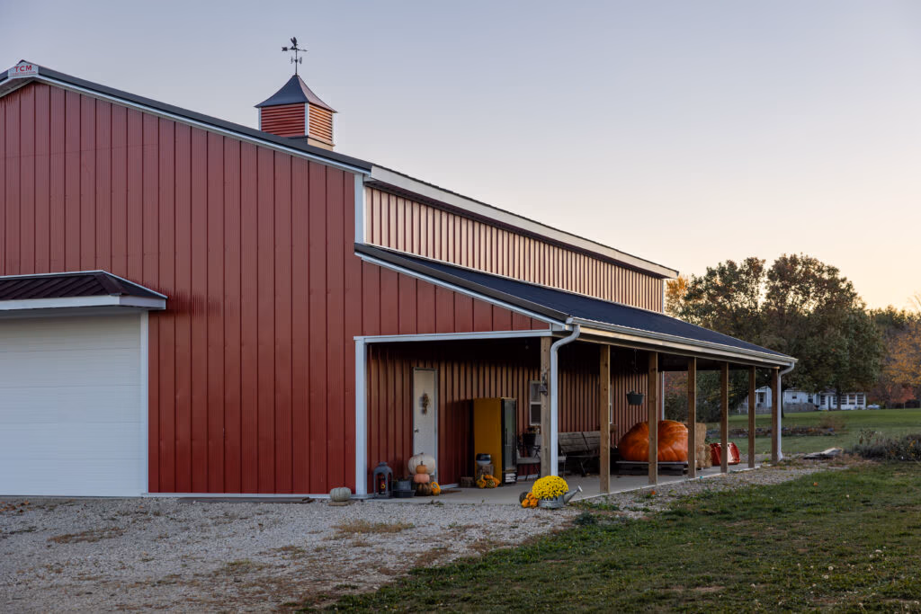 Red metal-sided barn with white trim and covered porch area, demonstrating Buckeye Wave panel installation on exterior wall