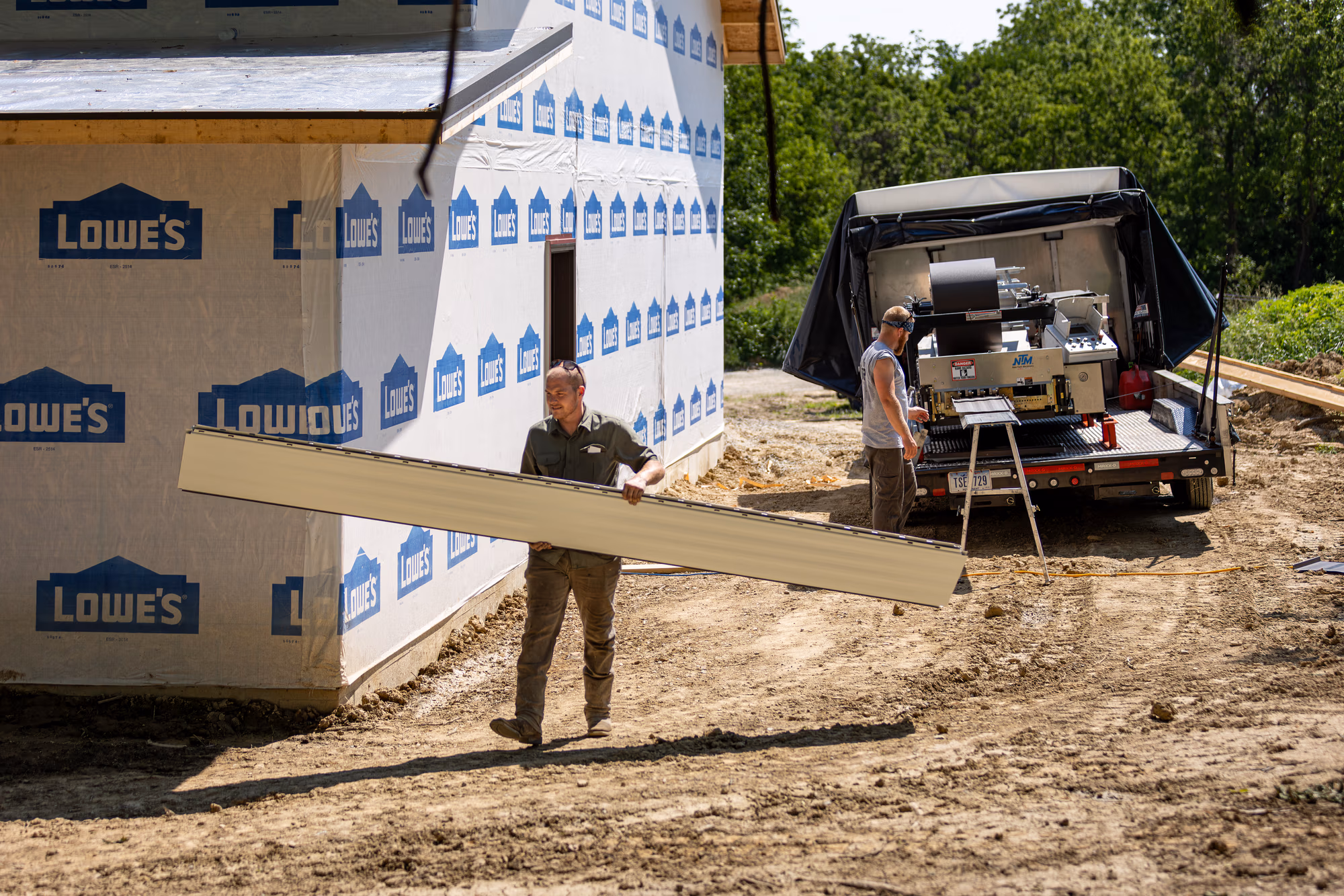 Buckeye Metal Sales portable rollformer truck parked at a construction site with stacked metal panels and building materials