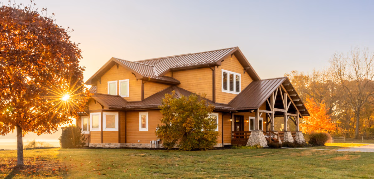 Residential home with metal roofing and siding, photographed during golden hour with manicured lawn and trees