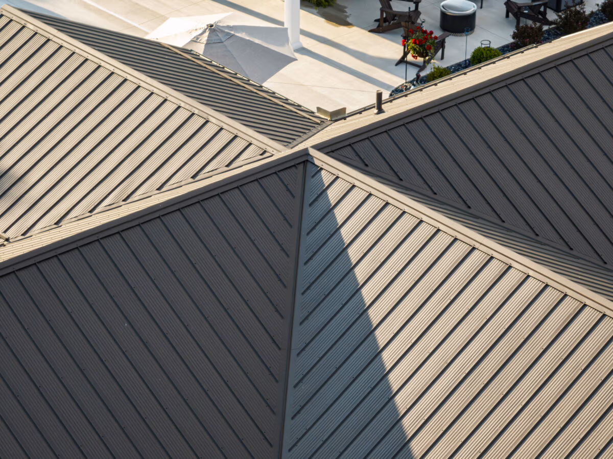 Overhead view of intersecting metal roof panels in light and dark gray with metal flashing at the peak